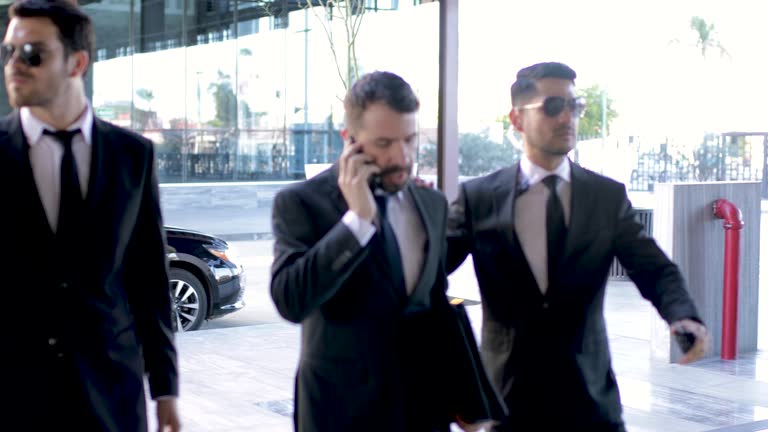 Security team escorting and protecting an important businessman out of a car and into a building